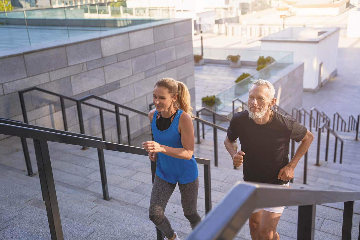 photo of a woman and a man exercising by running up stairs from an outdoor square
