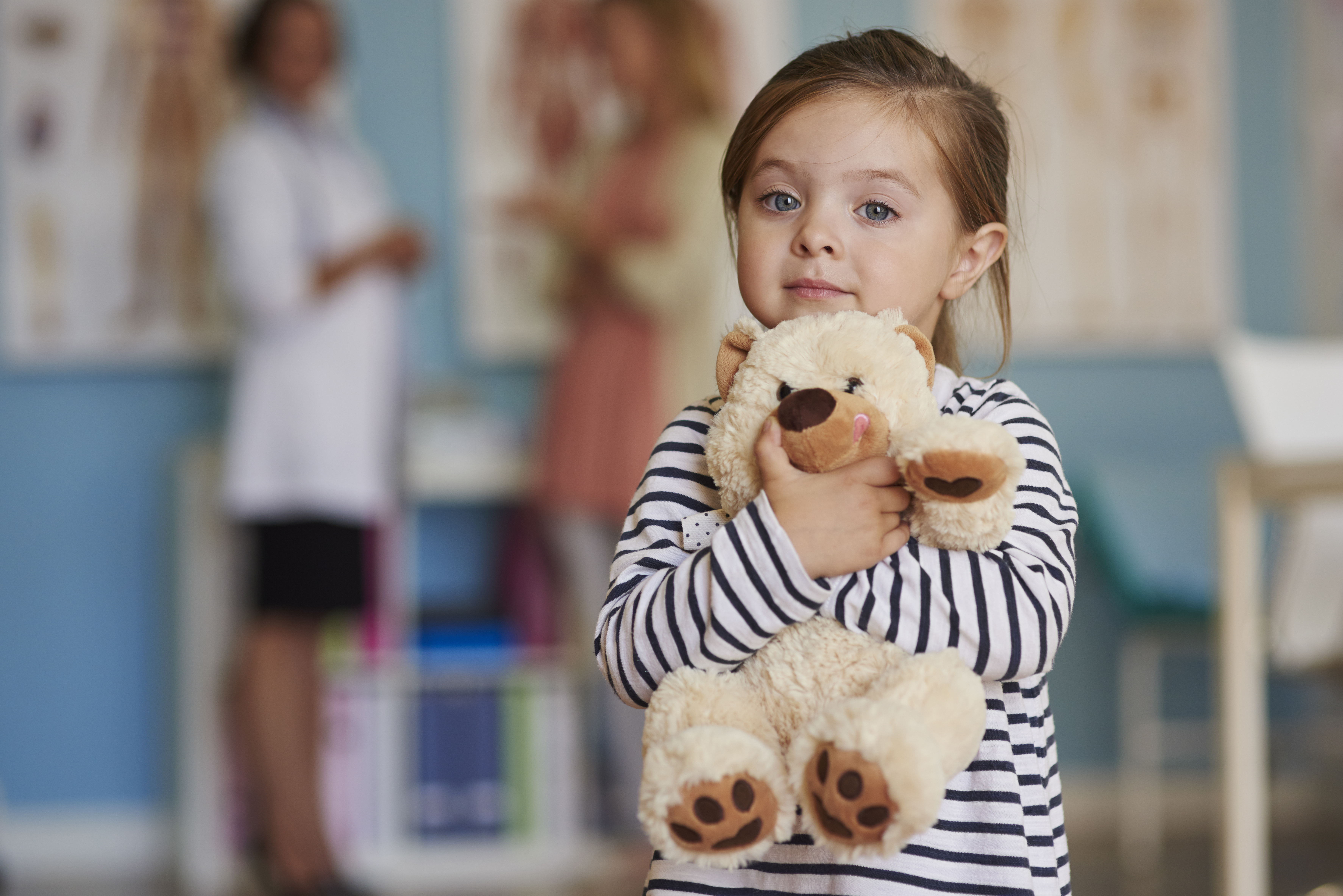 Child holds stuffed animal in hospital environment