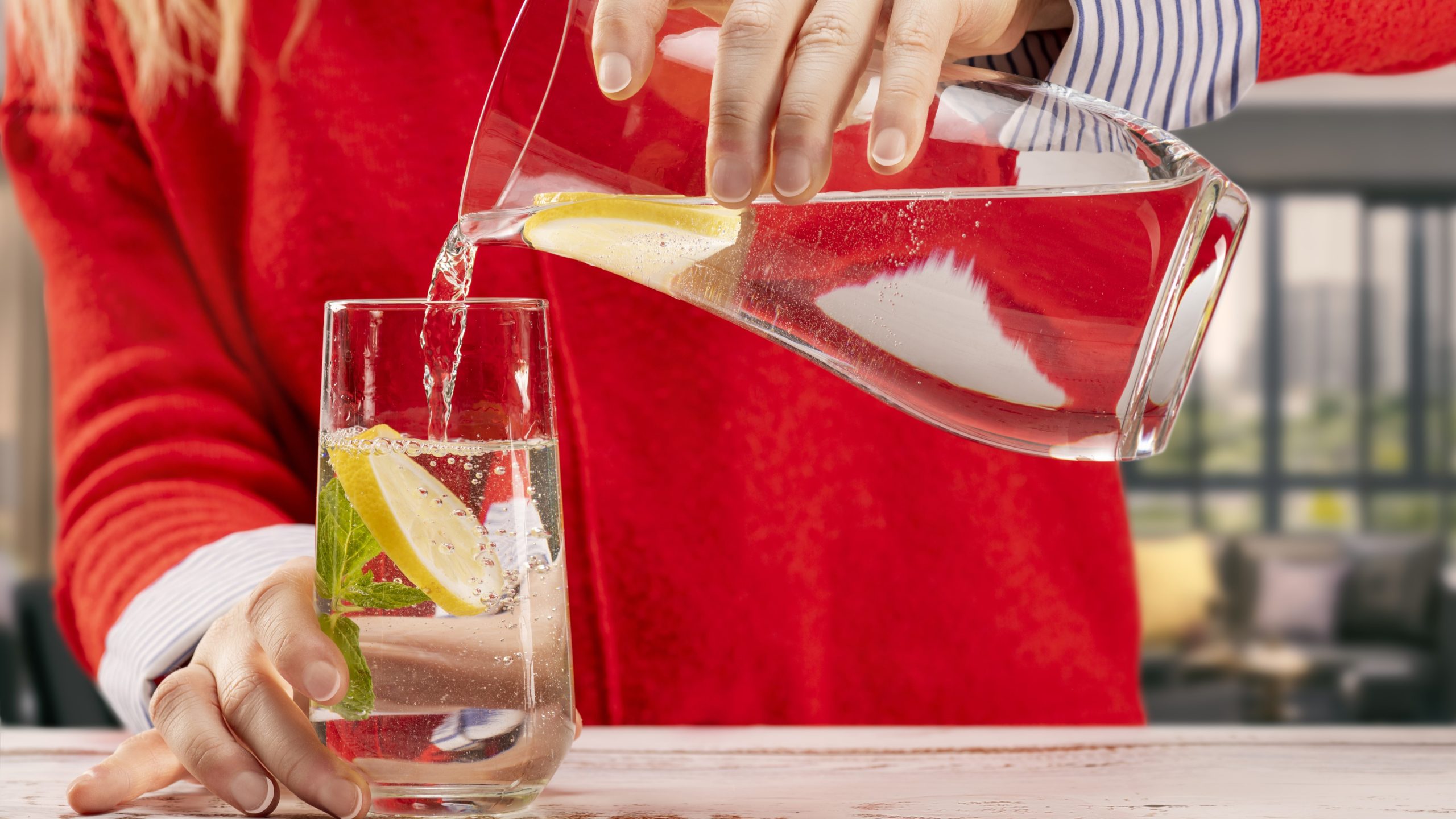 an image of a pitcher of water with lemon slices being poured into a glass.