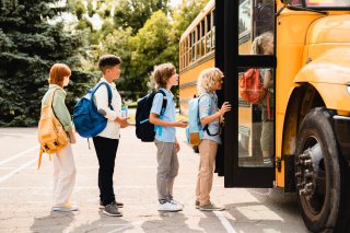 Children queue to get on the school bus